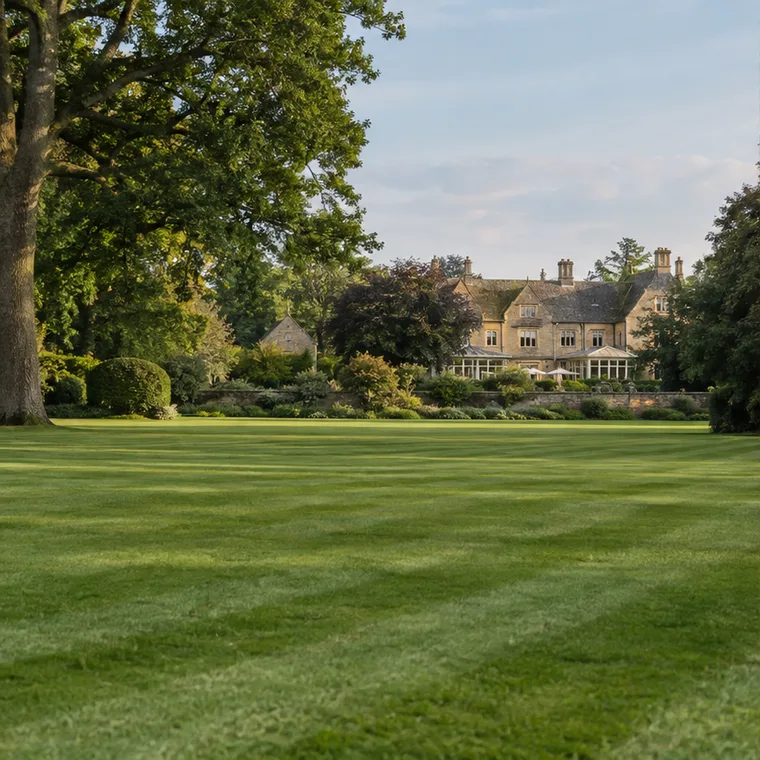 Illustrative English estate lawn with mature trees and a stone building