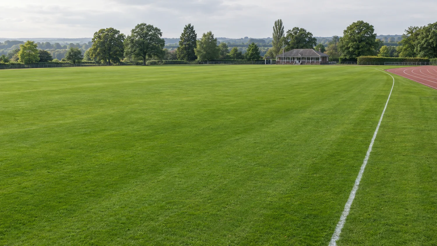Illustrative grass sports field alongside an athletics track